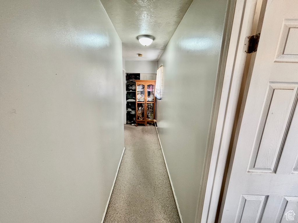 Hallway with baseboards and a textured ceiling