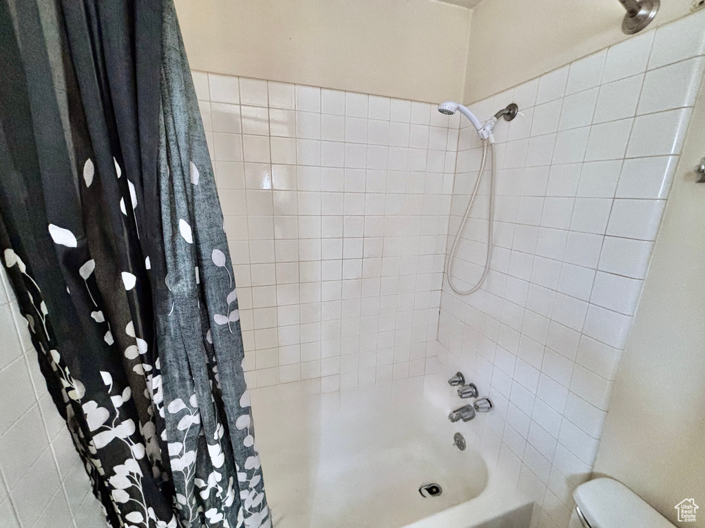 Bathroom with shower / bath combination with curtain and toilet