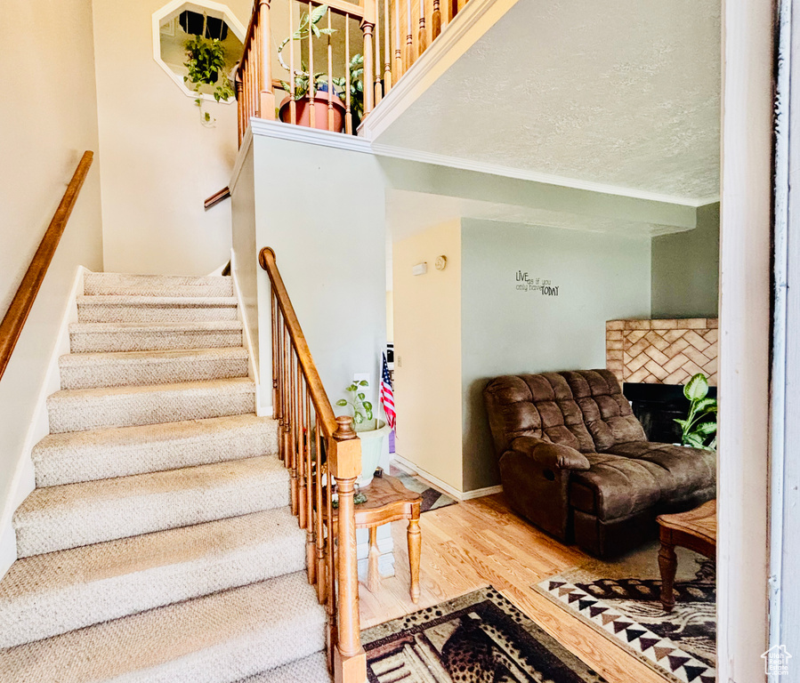 Staircase featuring wood finished floors and a fireplace