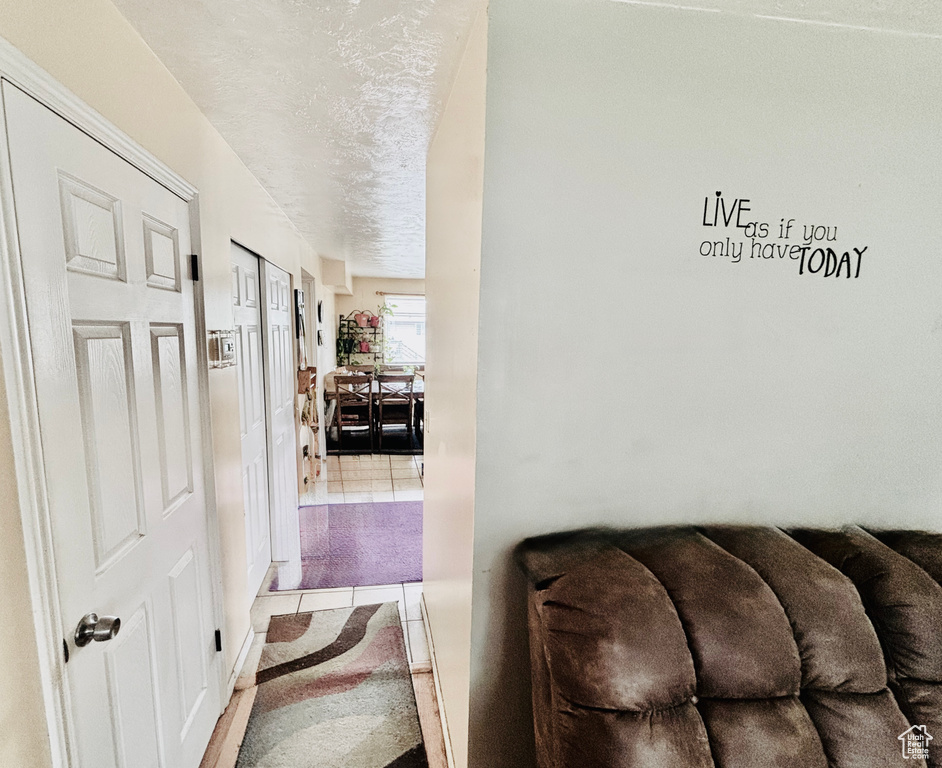 Hallway featuring tile patterned floors and a textured ceiling