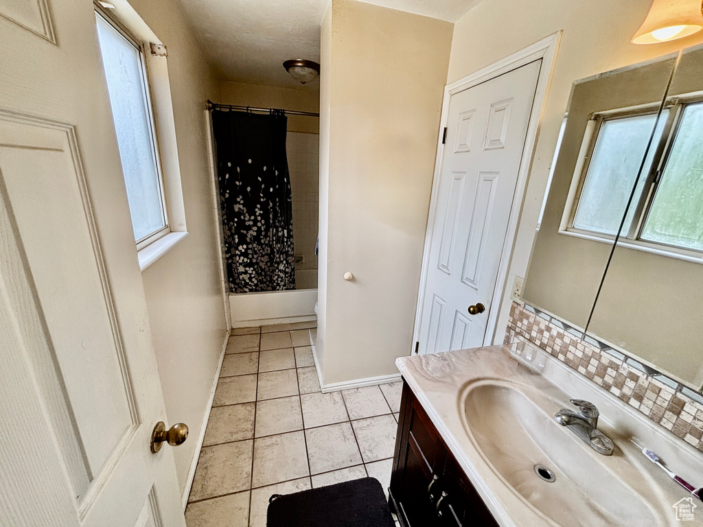 Full bathroom with vanity, decorative backsplash, and shower / bathtub combination with curtain