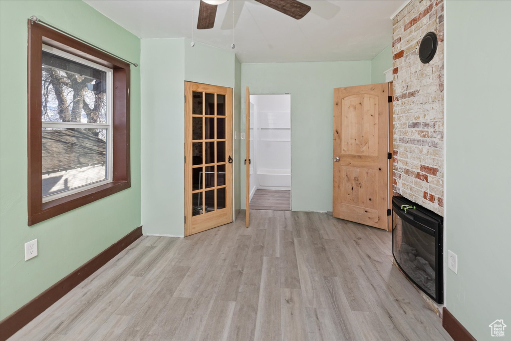 Spare room with a ceiling fan, light wood-style flooring, and a fireplace