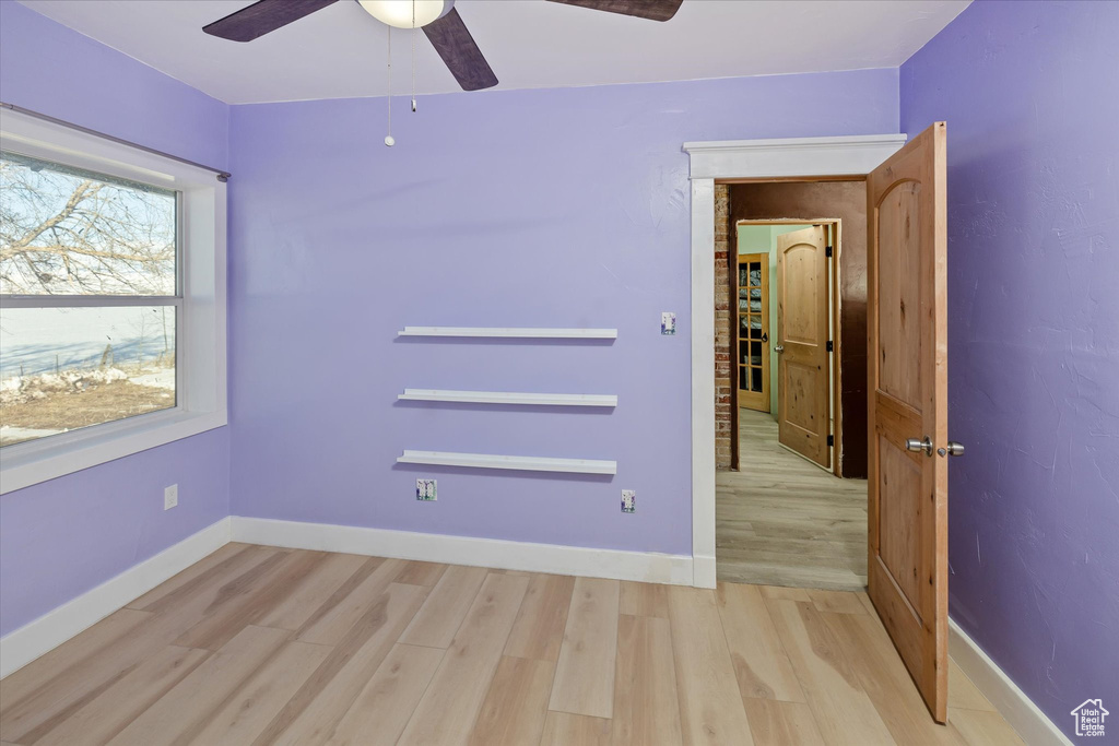 Empty room with light wood-style floors and a ceiling fan