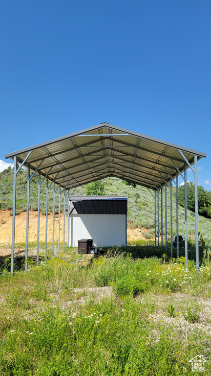 View of parking featuring a storage shed and a carport