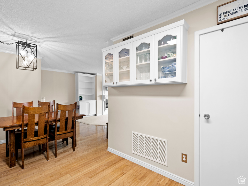 Dining area with crown molding and light wood-style floors