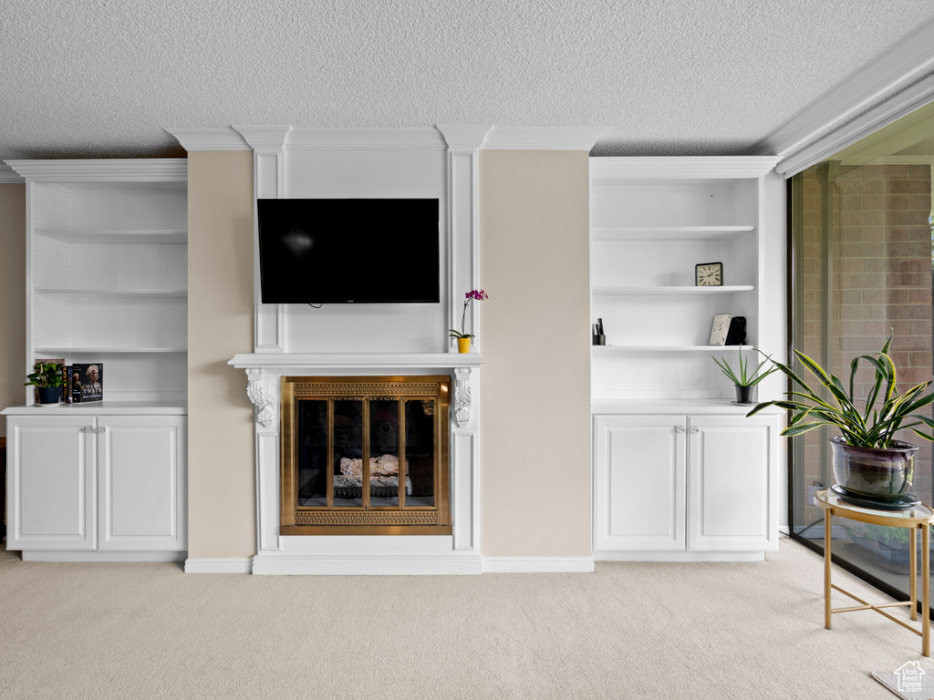 Unfurnished living room with a textured ceiling, light colored carpet, and ornamental molding