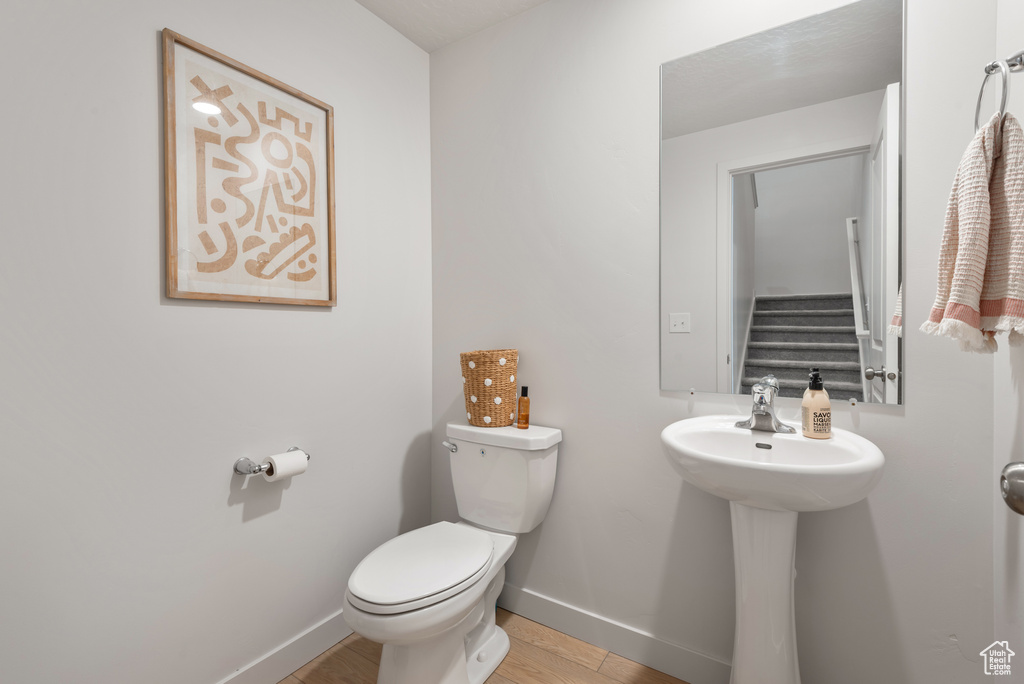 Half bathroom featuring toilet and wood finished floors