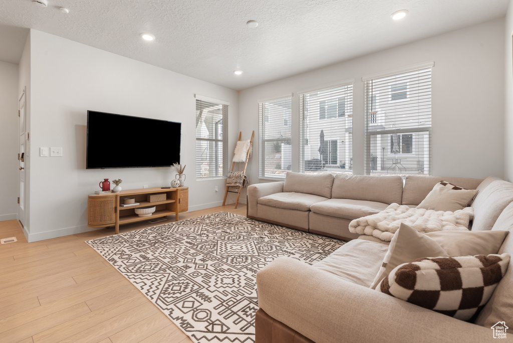 Living room with light wood-style flooring, recessed lighting, and a textured ceiling