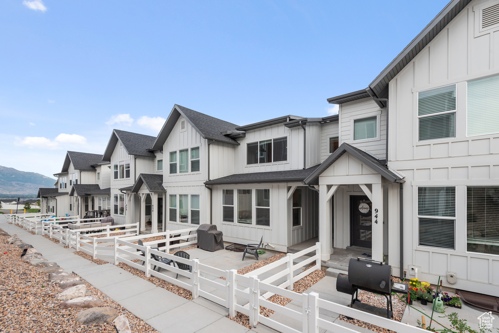 View of front of house with board and batten siding, a fenced front yard, a mountain view, a gate, and a shingled roof