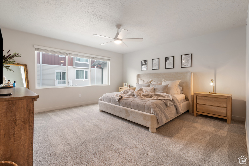 Carpeted bedroom with a ceiling fan and a textured ceiling
