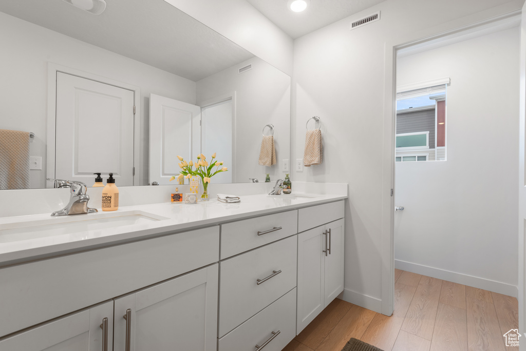 Bathroom with double vanity and wood finished floors