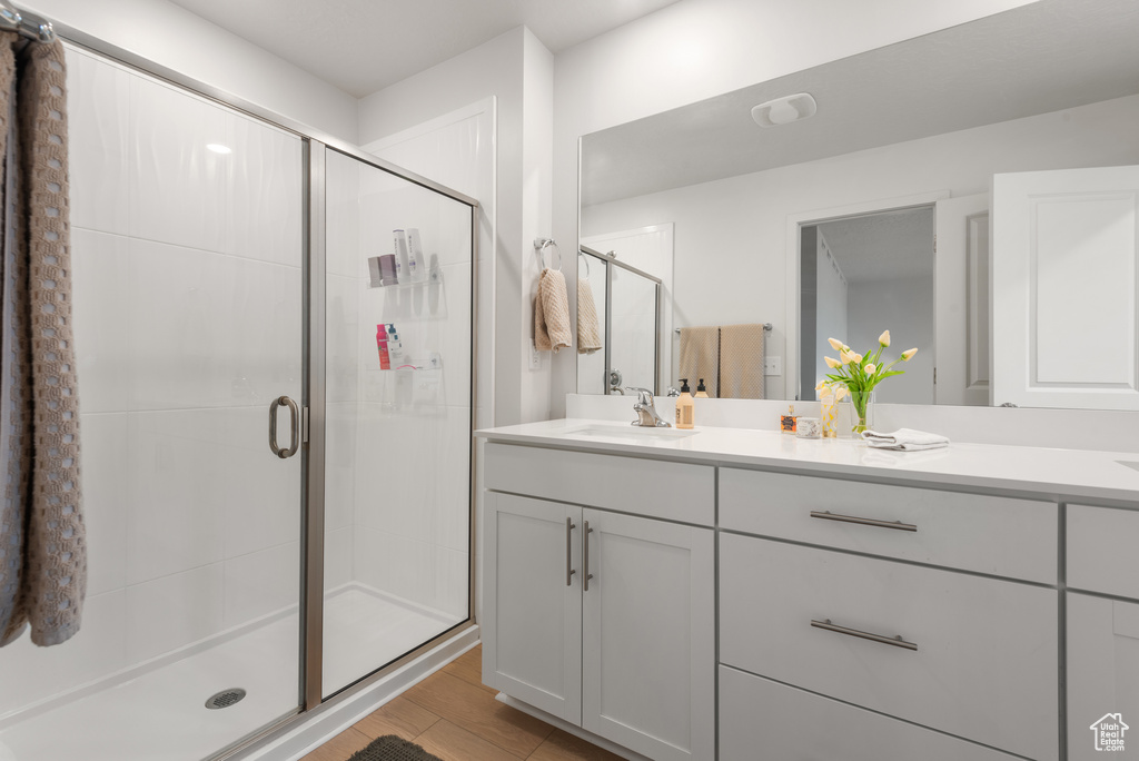 Bathroom with vanity, a shower stall, and wood finished floors