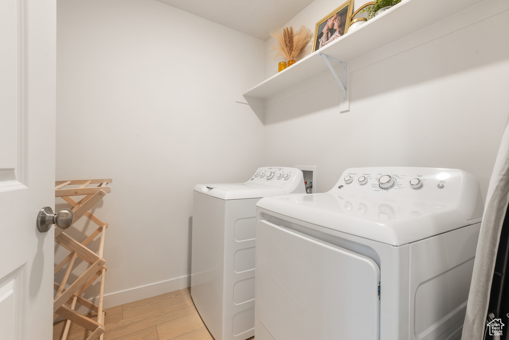 Laundry area with separate washer and dryer and light wood-style flooring