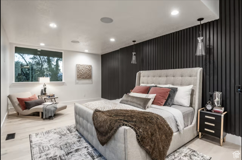 Bedroom with an accent wall, recessed lighting, and wood finished floors