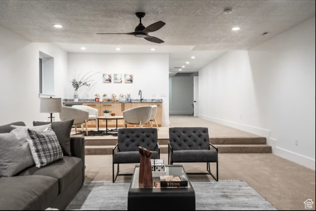 Living area with light carpet, ceiling fan, a textured ceiling, and recessed lighting