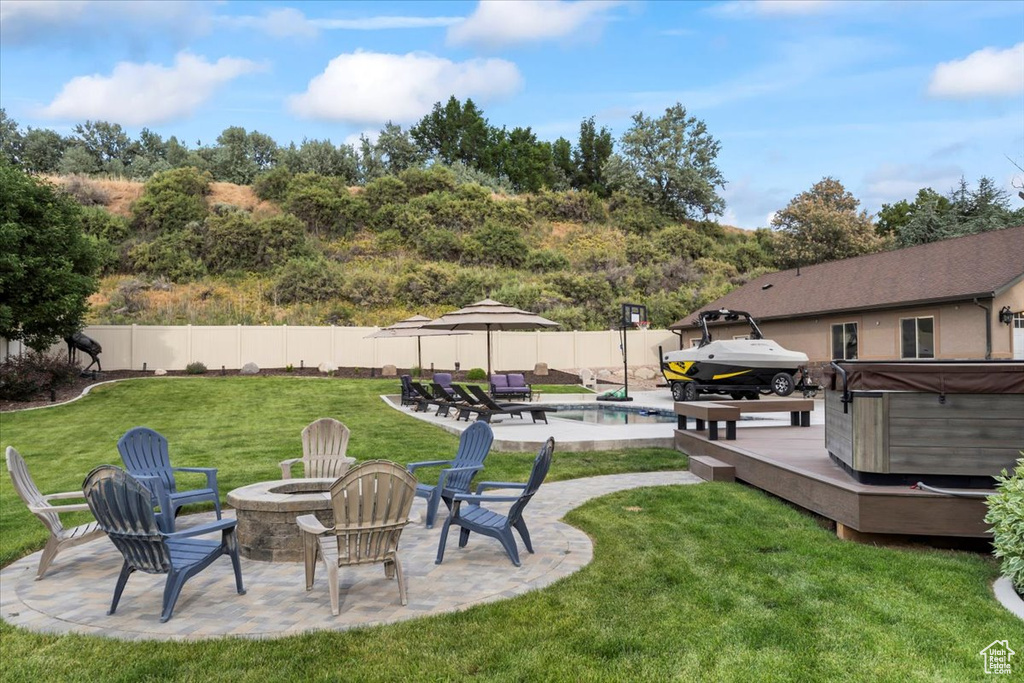 Fenced backyard with a hot tub, a fire pit, a patio area, and a deck