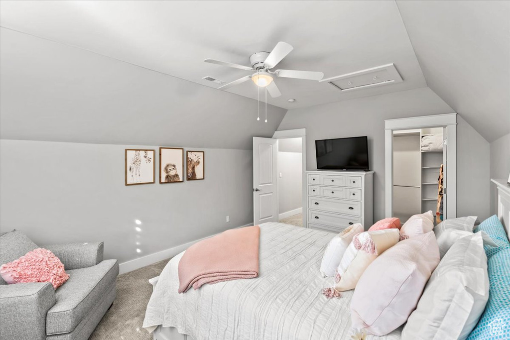 Carpeted bedroom with vaulted ceiling, a ceiling fan, and a spacious closet