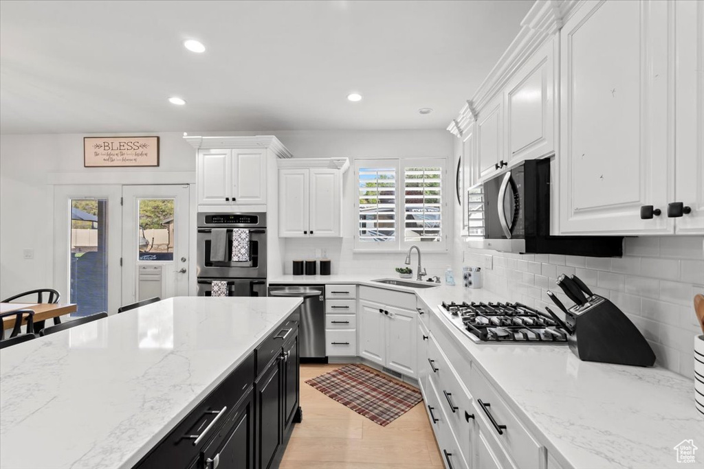 Kitchen with dark cabinetry, white cabinetry, appliances with stainless steel finishes, backsplash, and recessed lighting