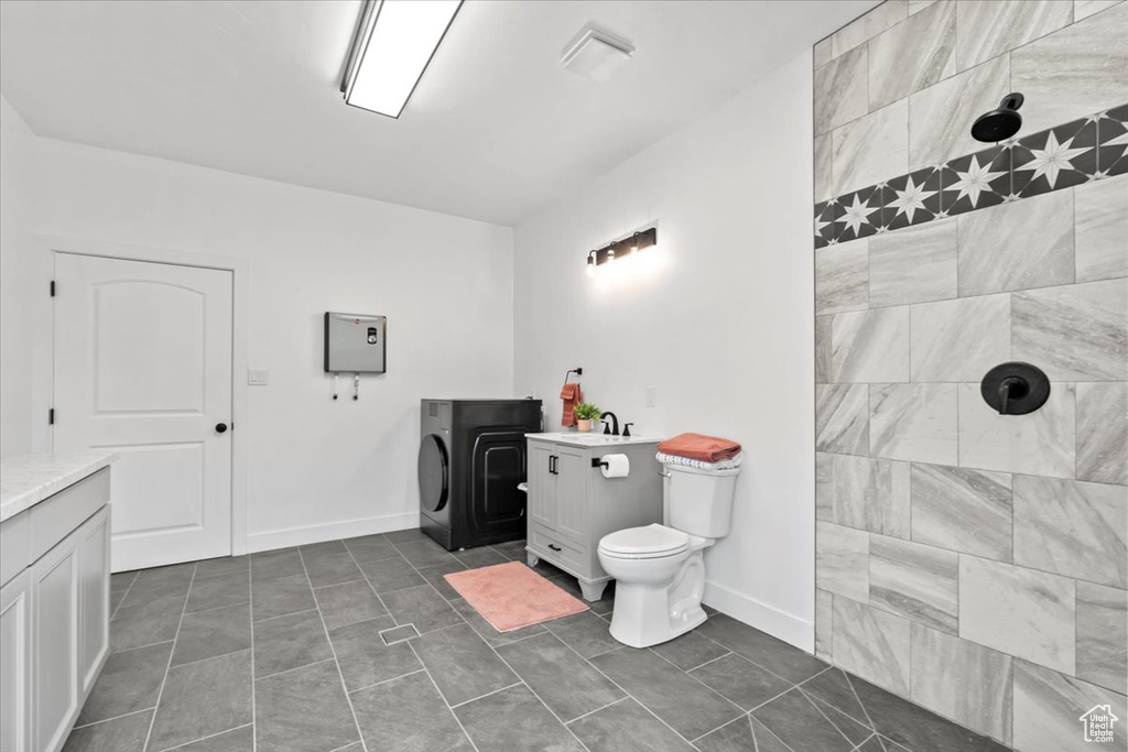 Full bath featuring vanity, tiled shower, and tile patterned flooring
