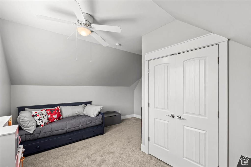 Carpeted bedroom with lofted ceiling, a ceiling fan, and a closet