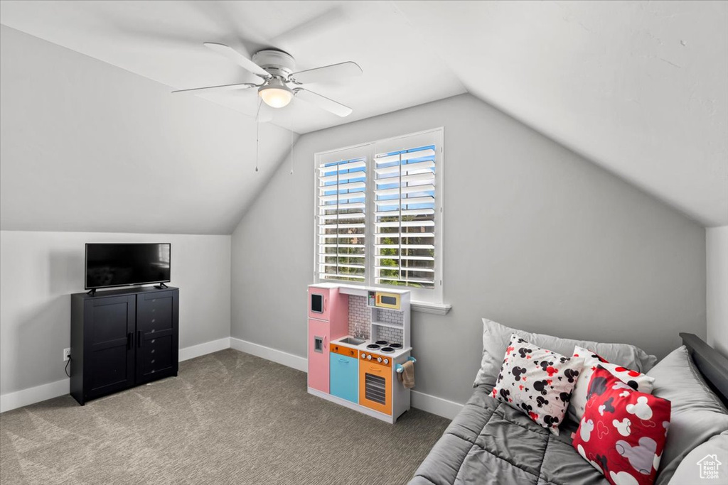 Carpeted bedroom featuring vaulted ceiling and ceiling fan