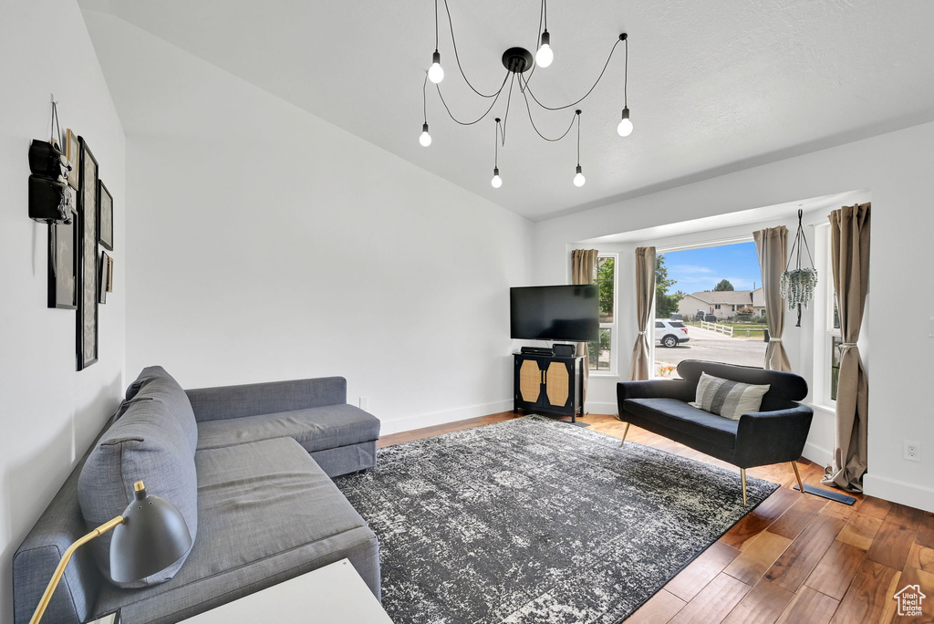 Living area with vaulted ceiling, wood finished floors, and a chandelier