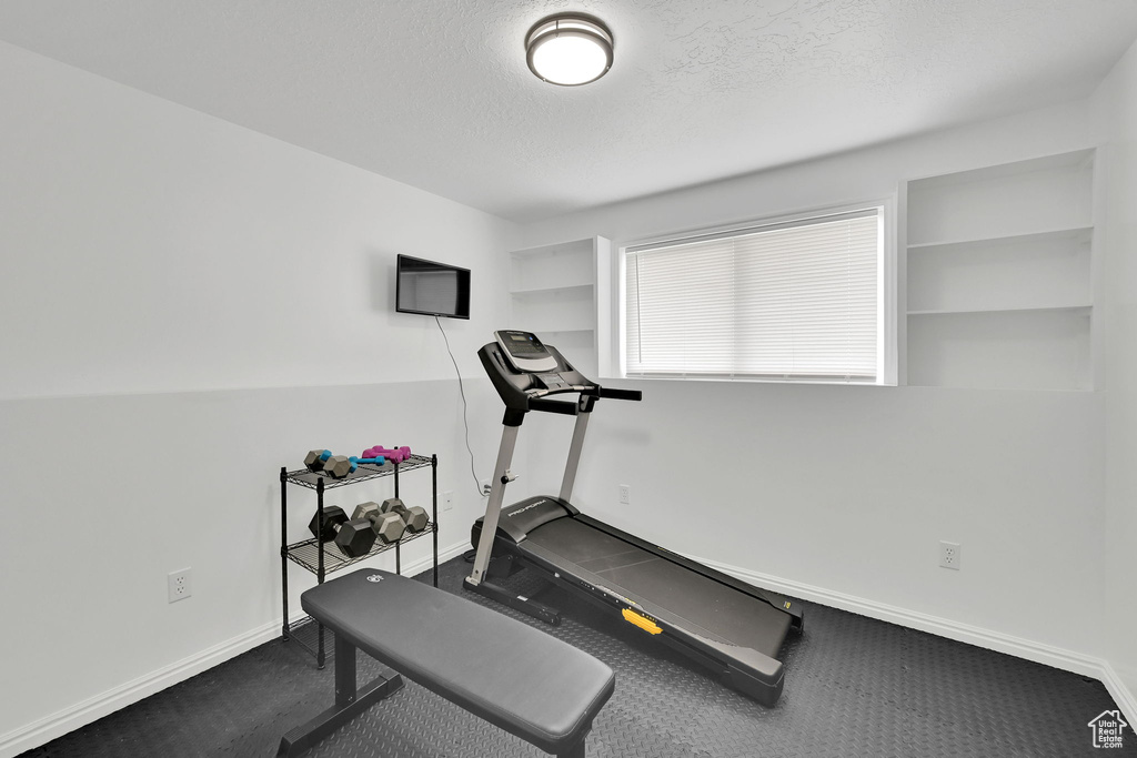 Exercise room with baseboards and a textured ceiling