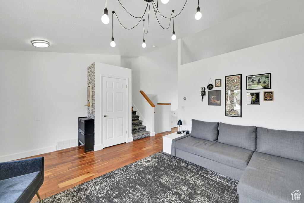 Living room featuring stairs, wood finished floors, and a chandelier