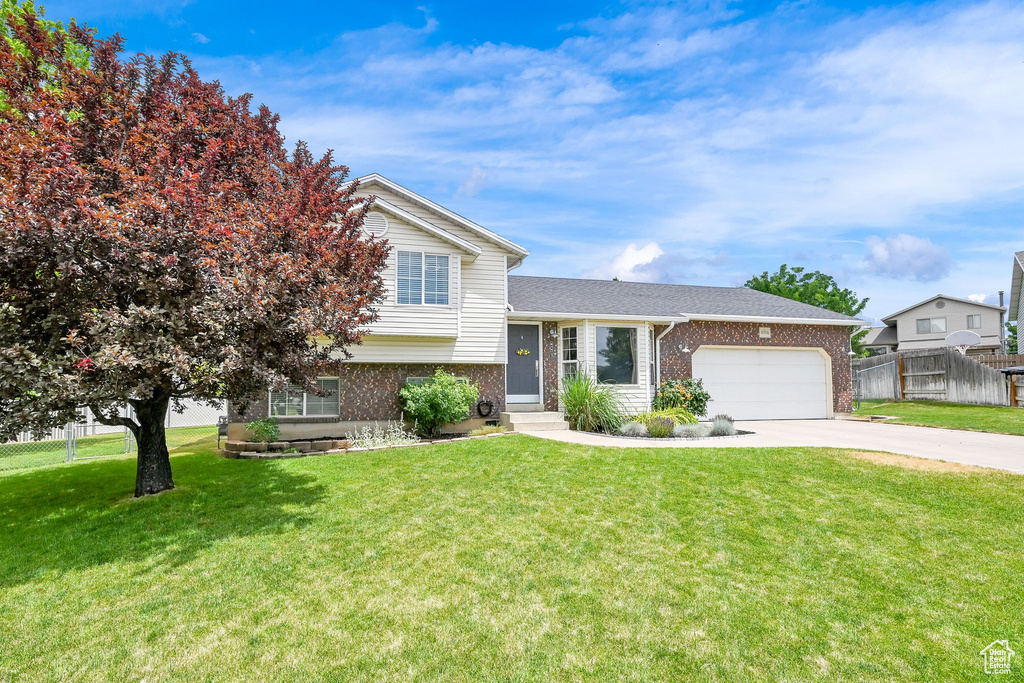Split level home with brick siding, a garage, and concrete driveway