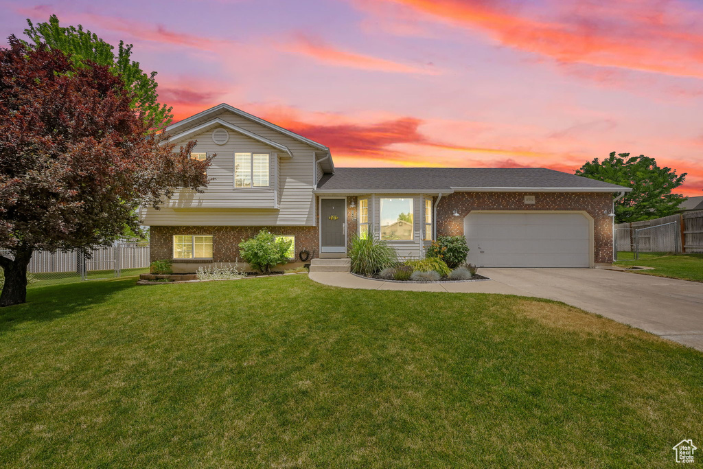 Tri-level home featuring brick siding, an attached garage, and driveway