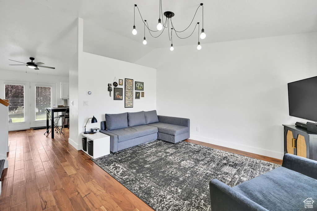 Living area featuring wood finished floors, a chandelier, ceiling fan, and lofted ceiling
