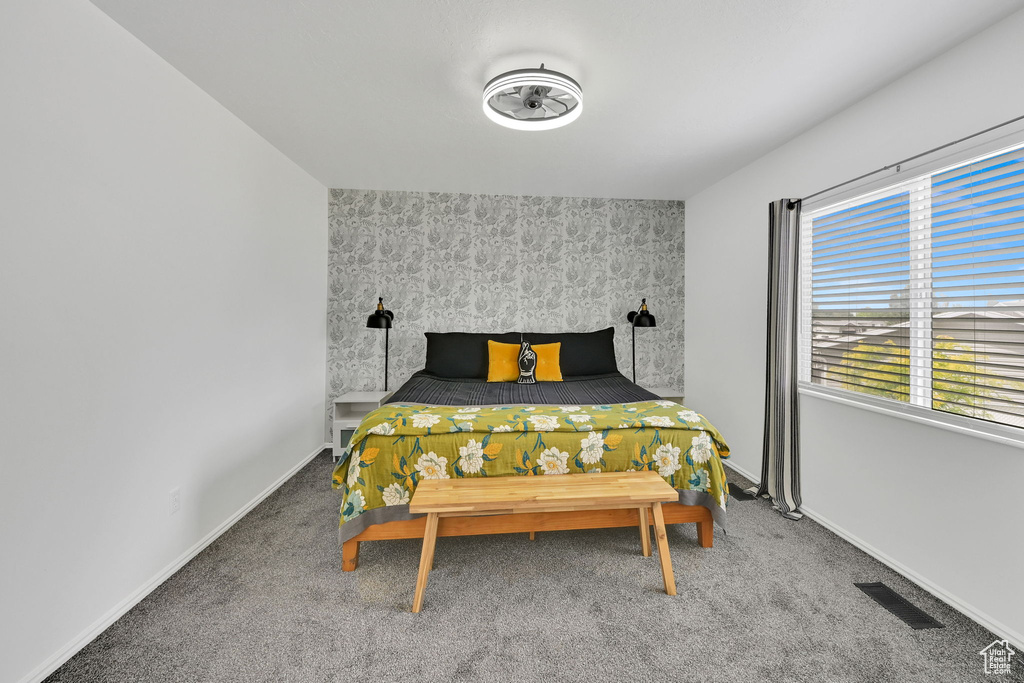 Carpeted bedroom with an accent wall and baseboards