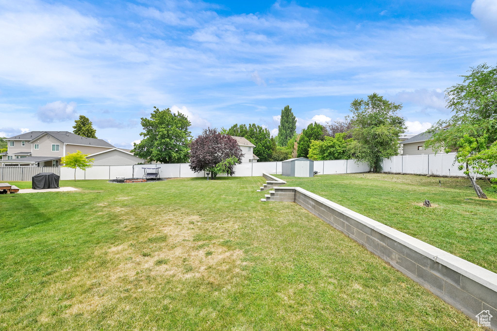 Fenced backyard featuring a storage unit and a residential view