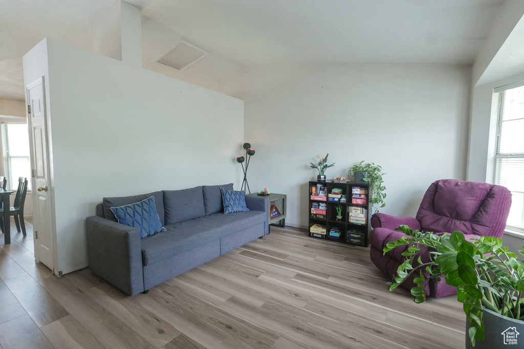 Living area with light wood-style floors and lofted ceiling