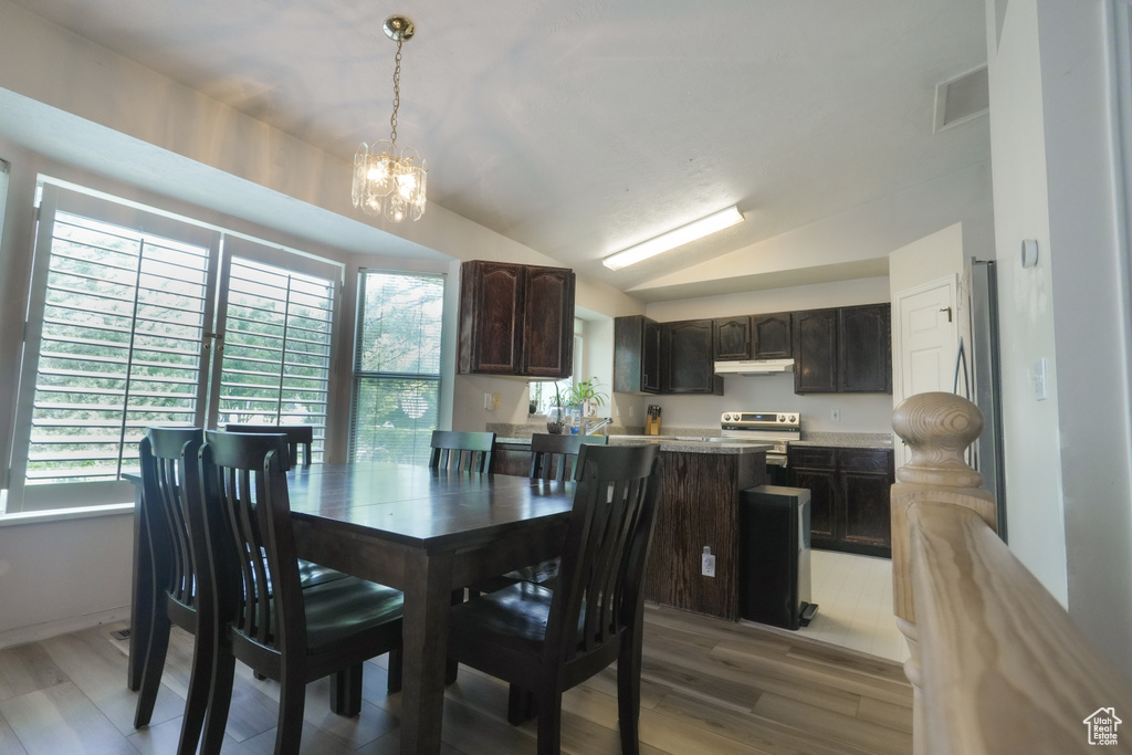 Dining area featuring a chandelier, light wood finished floors, and lofted ceiling