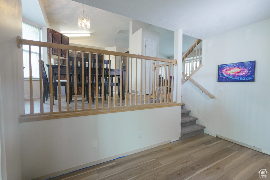 Stairs featuring wood finished floors and a chandelier