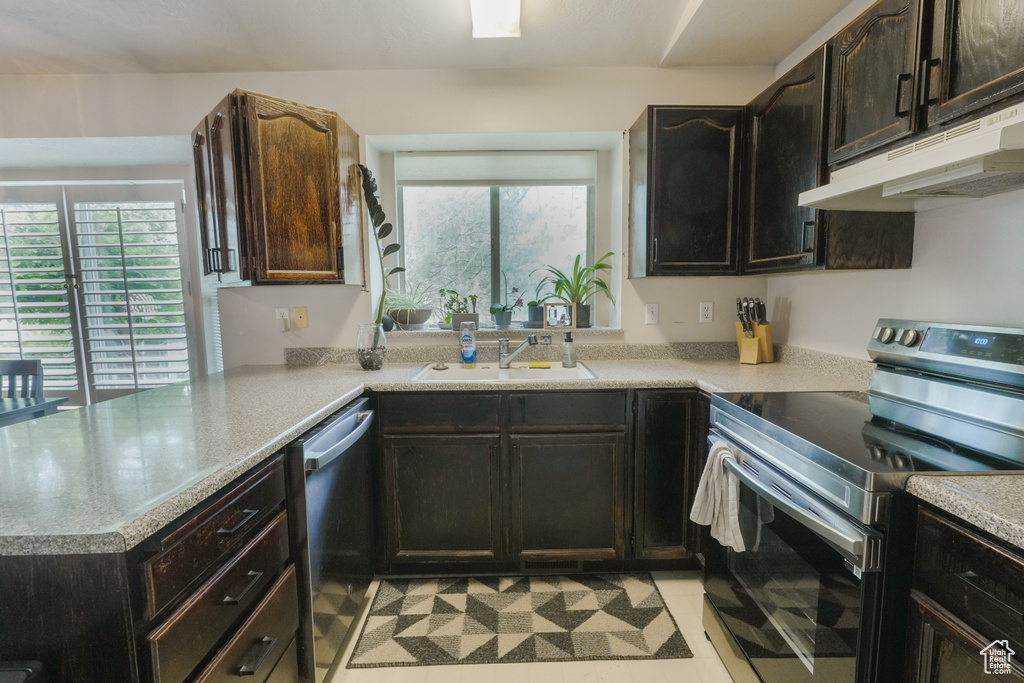 Kitchen with stainless steel appliances, under cabinet range hood, plenty of natural light, and a peninsula