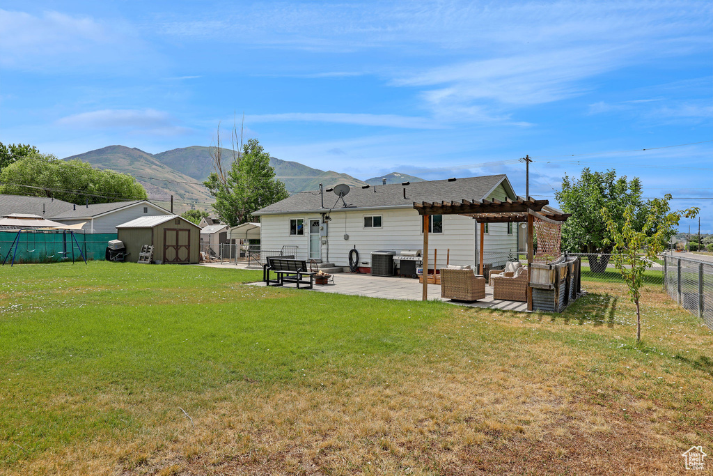 Rear view of house with outdoor lounge area, a pergola, a fenced backyard, a shed, and a patio area