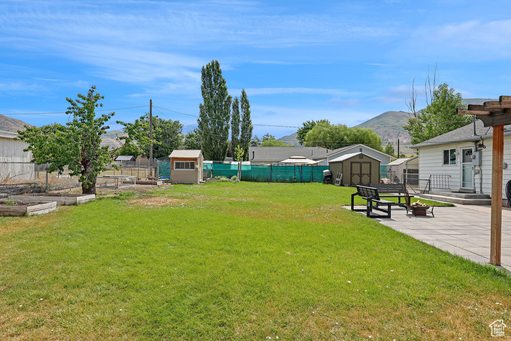 Fenced backyard with a storage shed, a patio, a garden, and a mountain view