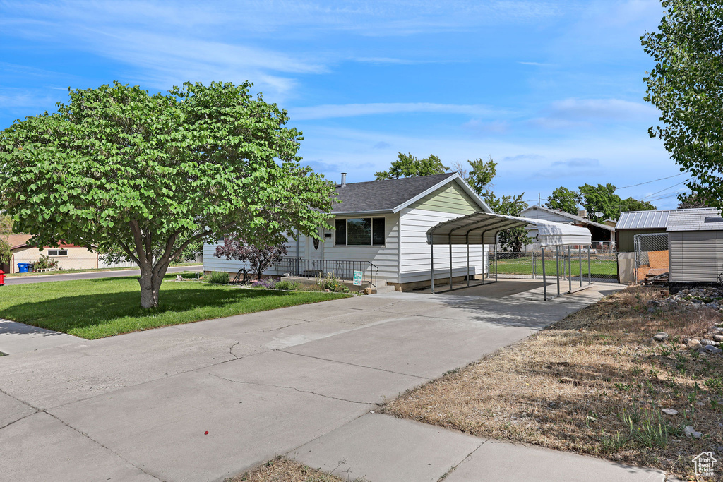View of front of home with a carport, driveway, and a shingled roof