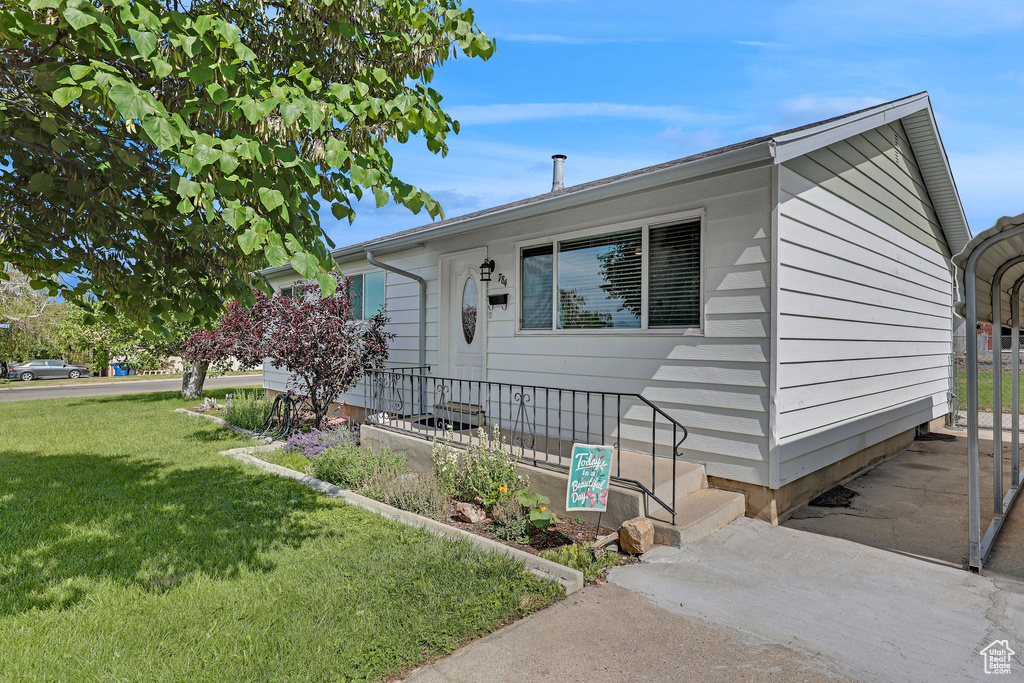Ranch-style home featuring a front lawn and a detached carport
