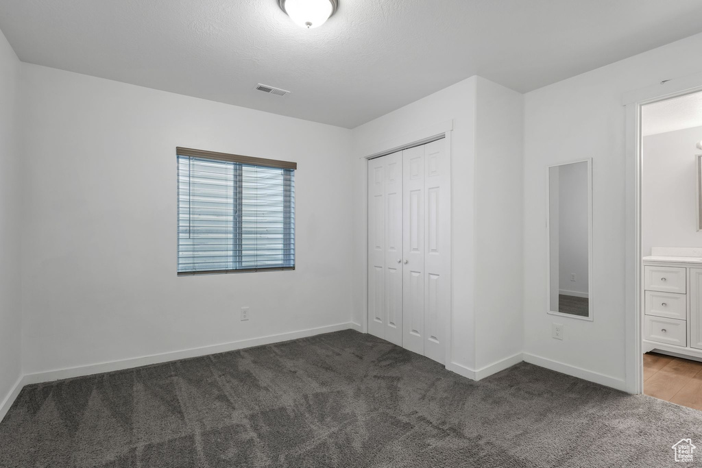 Unfurnished bedroom with carpet flooring, a closet, and ensuite bath