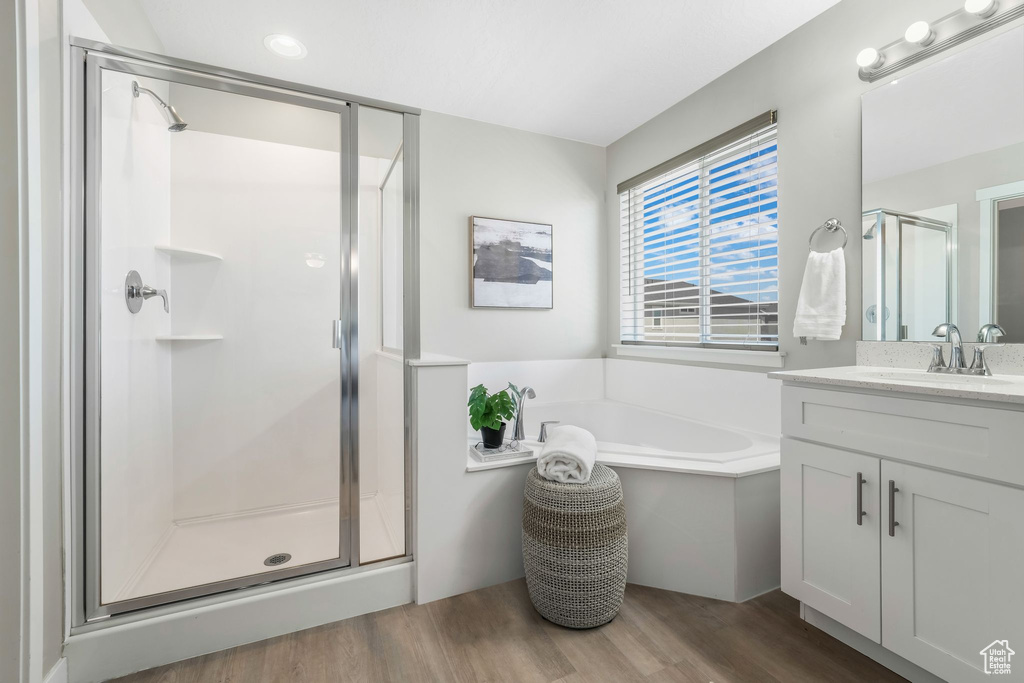 Bathroom featuring a stall shower, vanity, wood finished floors, and a garden tub