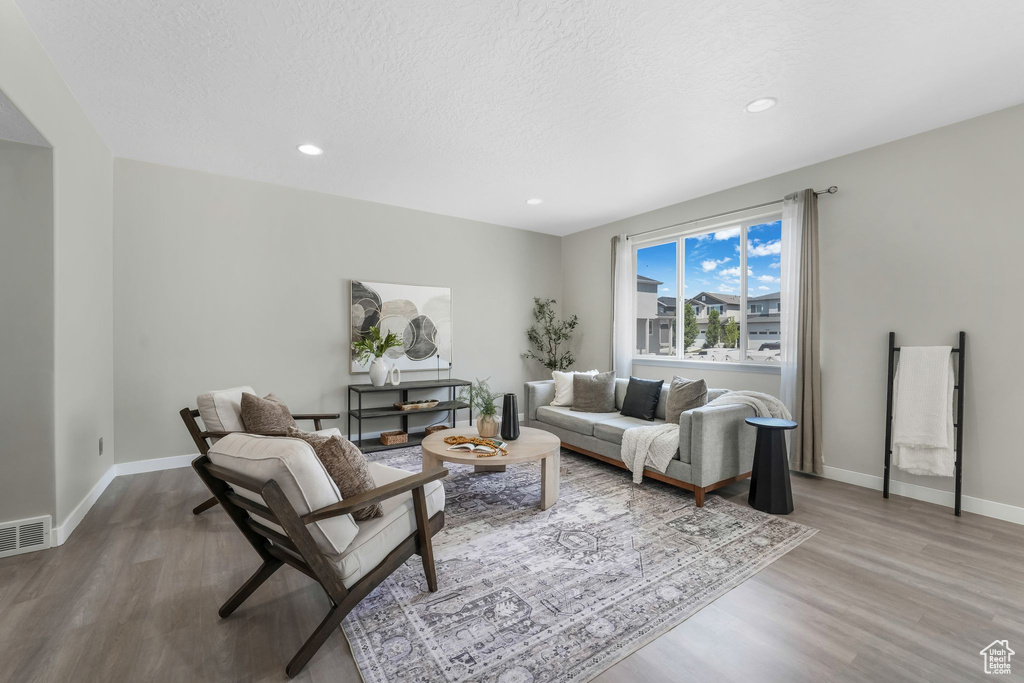 Living room with wood finished floors, recessed lighting, and a textured ceiling