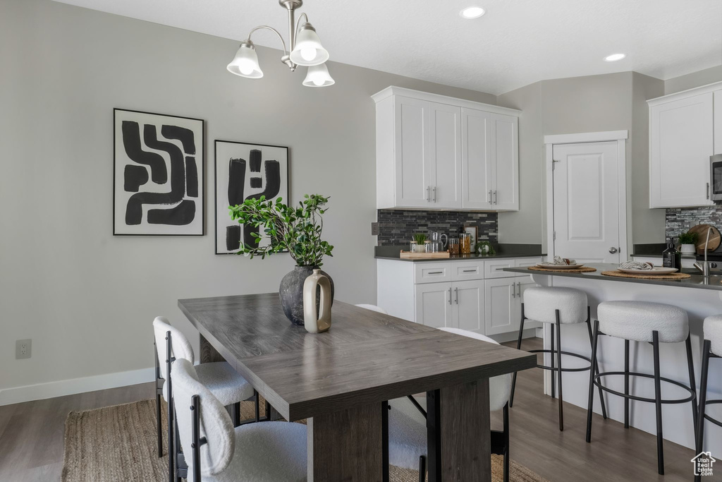 Dining space featuring dark wood finished floors, recessed lighting, and a chandelier