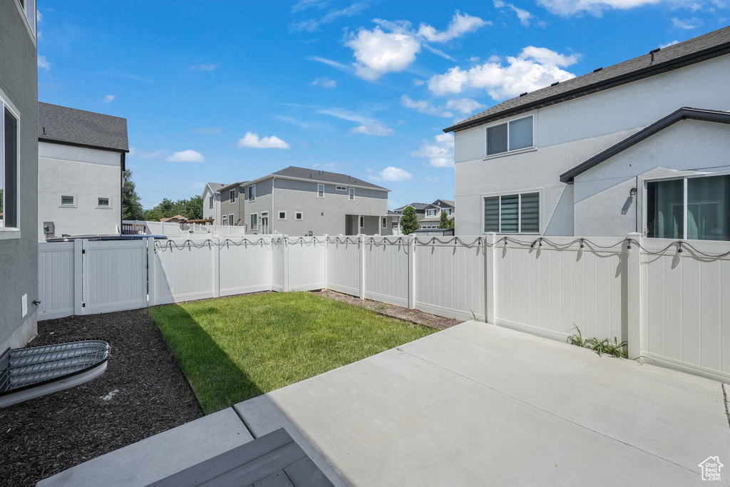 Fenced backyard featuring a residential view, a patio area, and a gate