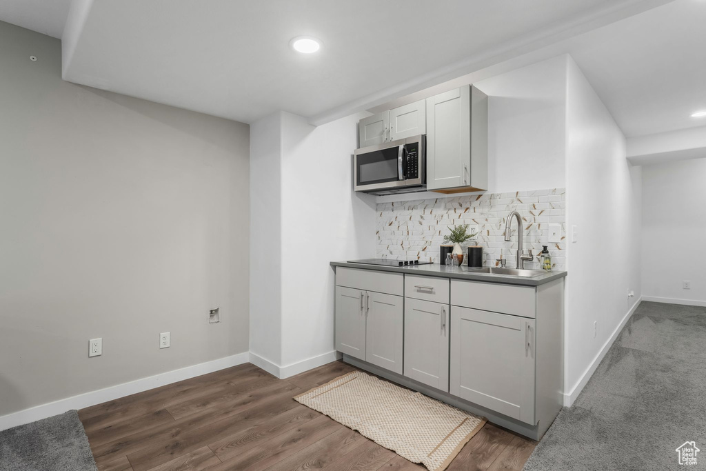 Kitchen with stainless steel microwave, backsplash, recessed lighting, dark wood-type flooring, and black electric stovetop