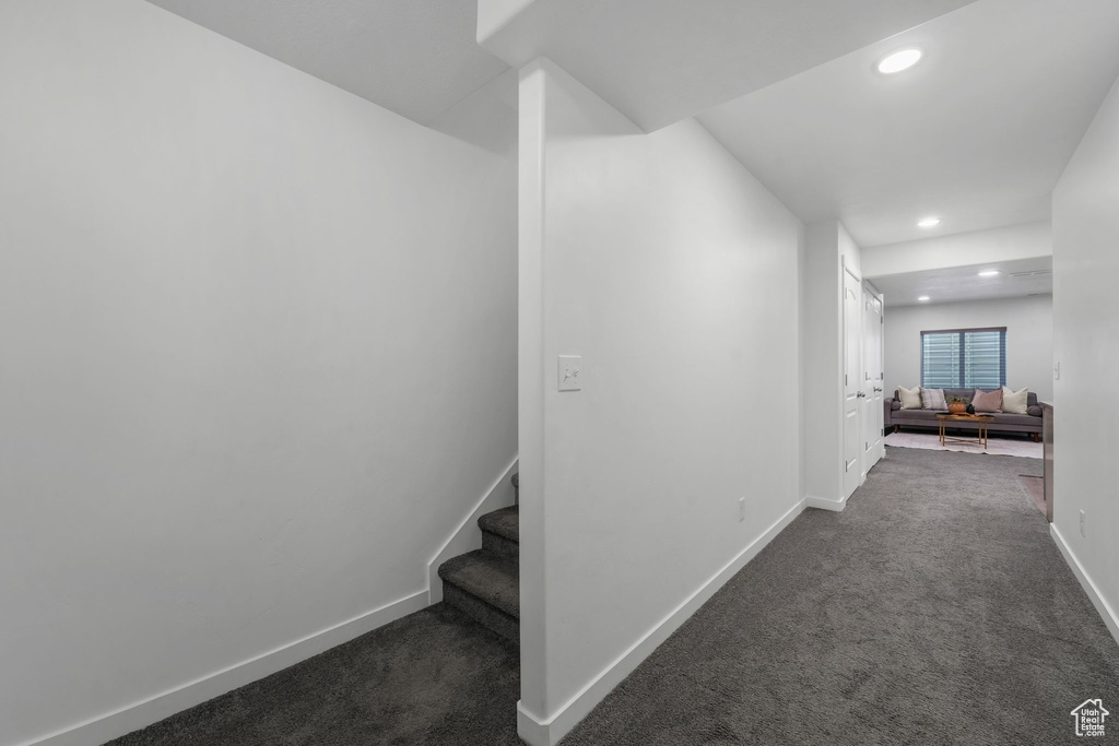 Hallway featuring recessed lighting, dark colored carpet, and stairway