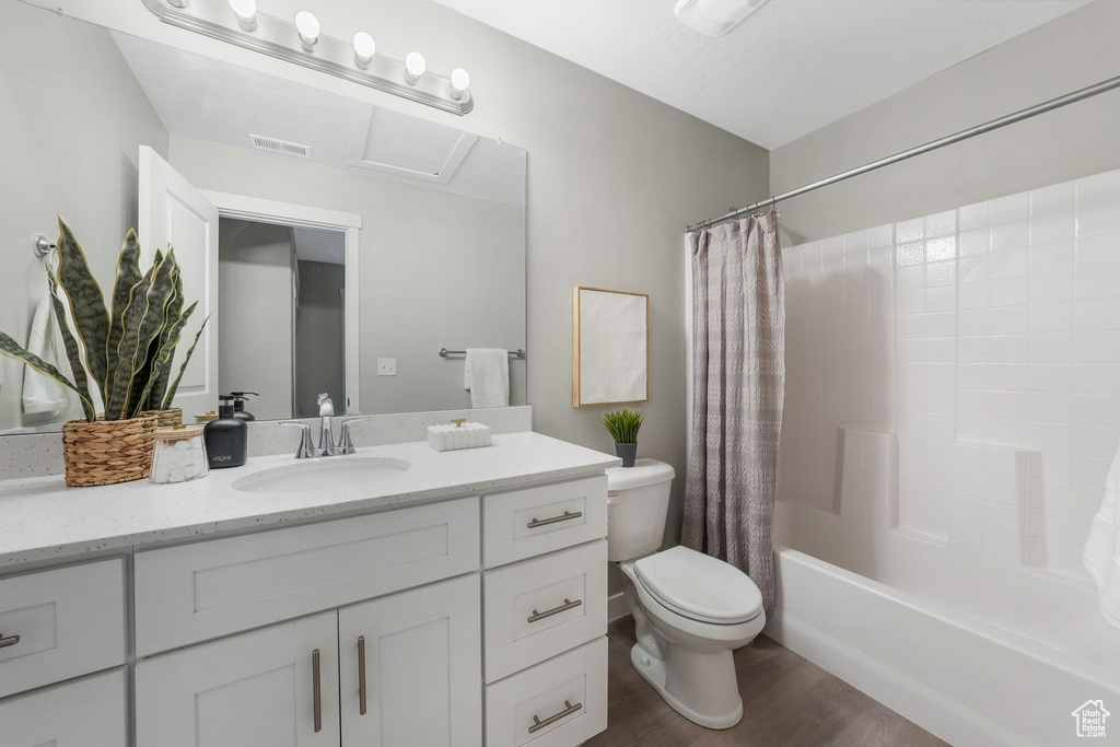 Bathroom with vanity, shower / bath combo, and wood finished floors