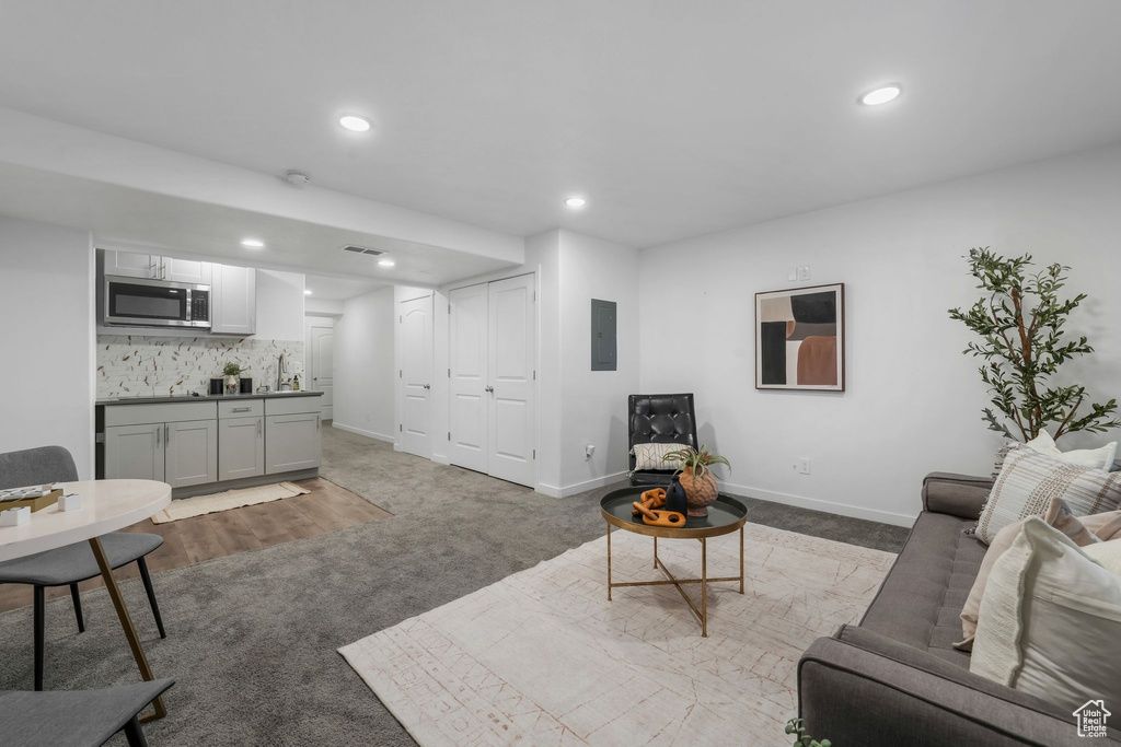 Living area featuring bar with sink, carpet flooring, electric panel, and recessed lighting
